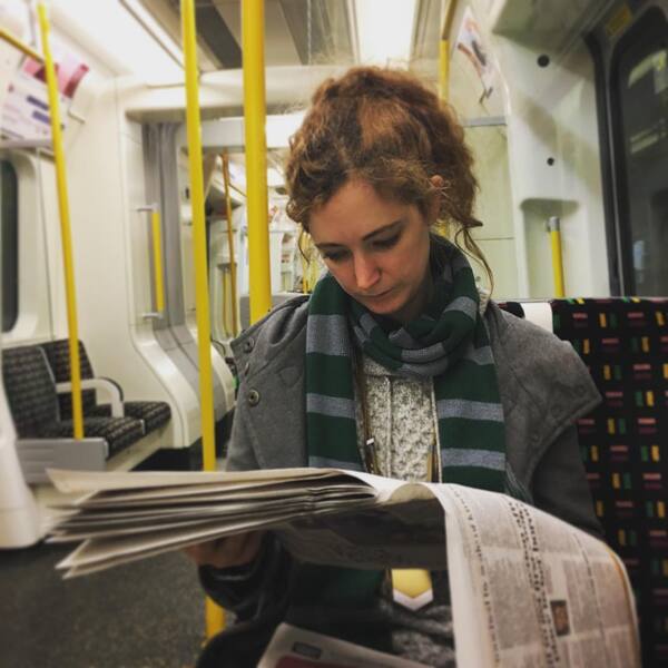 a woman reading a newspaper on a train