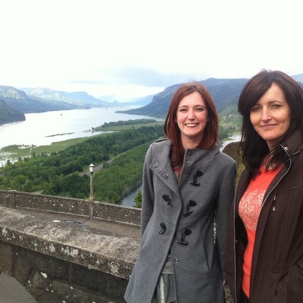 two women standing on a wall near a lake