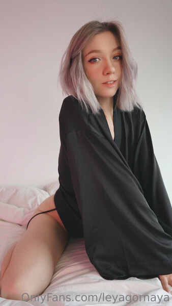 a woman with pink hair sitting on a bed