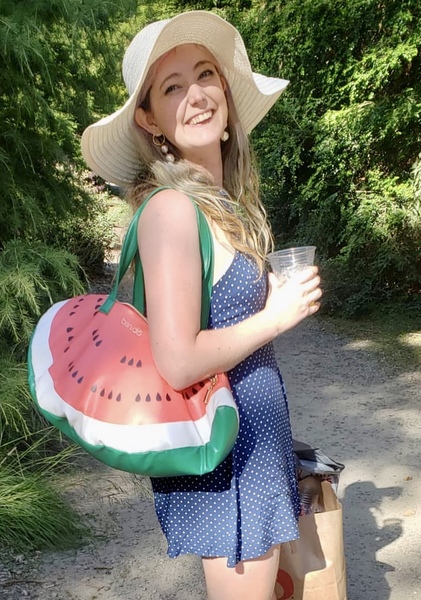 a woman in a hat and dress holding a watermelon