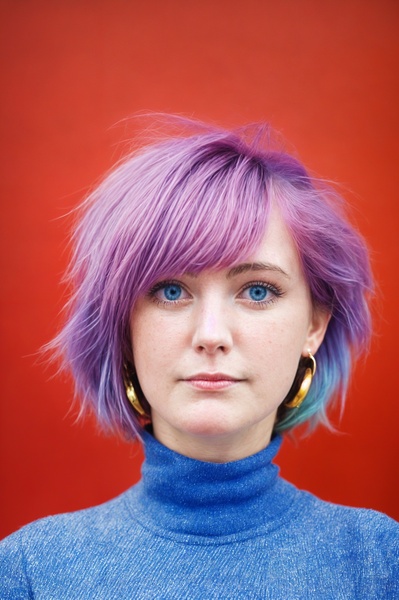 a woman with purple hair and blue sweater