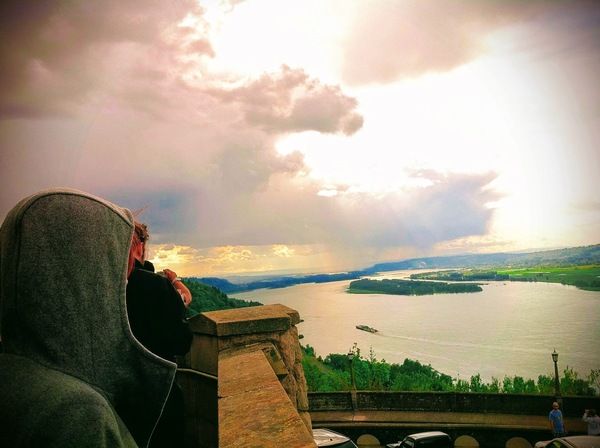 a person sitting on a ledge overlooking a lake