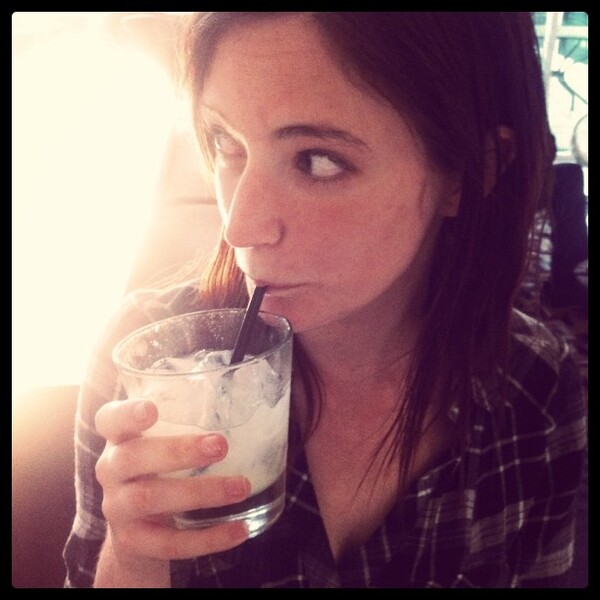 a woman drinking a drink in a glass for