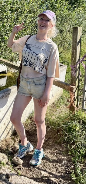 a woman in shorts and a hat standing next to a fence