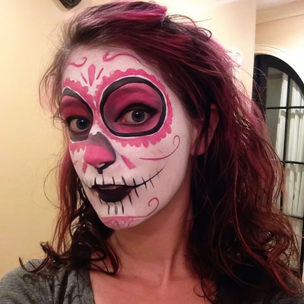 a woman with red hair and a face painted in pink