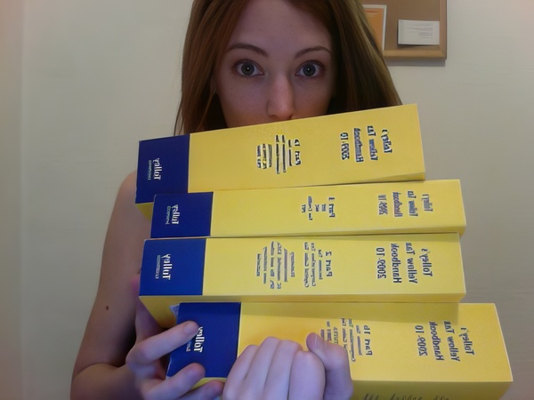 a woman holding a stack of yellow and blue boxes 4

en got wullaY
palace JoodknaH
ootal it} Spe,
er 1 OF -COUE