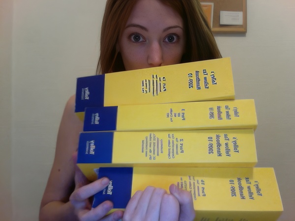 a woman holding a stack of yellow and blue boxes ' galtot
pula

iotal vata |e wy «=SCCU
oF 200k
ust wel