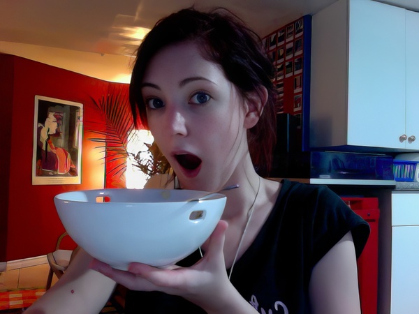 a woman eating a bowl of food in a kitchen