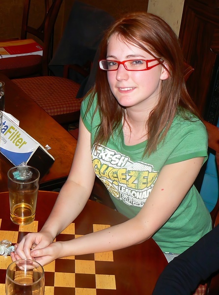 a girl sitting at a table with a glass of beer