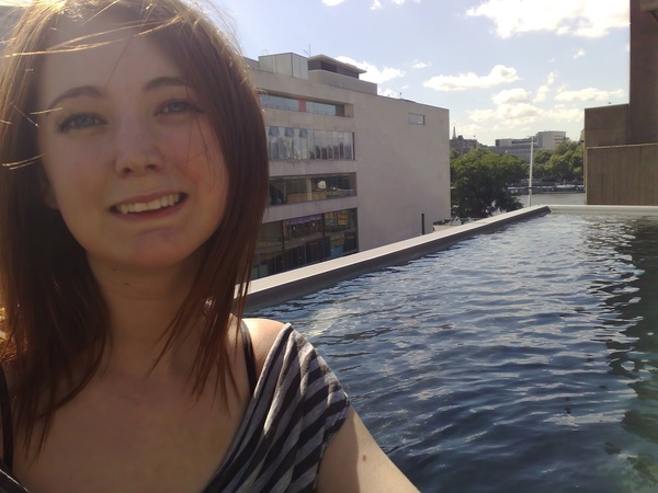 a woman standing in a pool with a building in the background