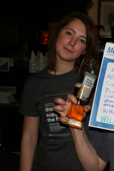 a woman holding a sign with a bottle of alcohol Ad