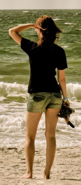 a woman standing on the beach with a surfboard