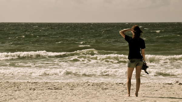 a woman standing on a beach with a kite in her hand eters ce

geht = ton: