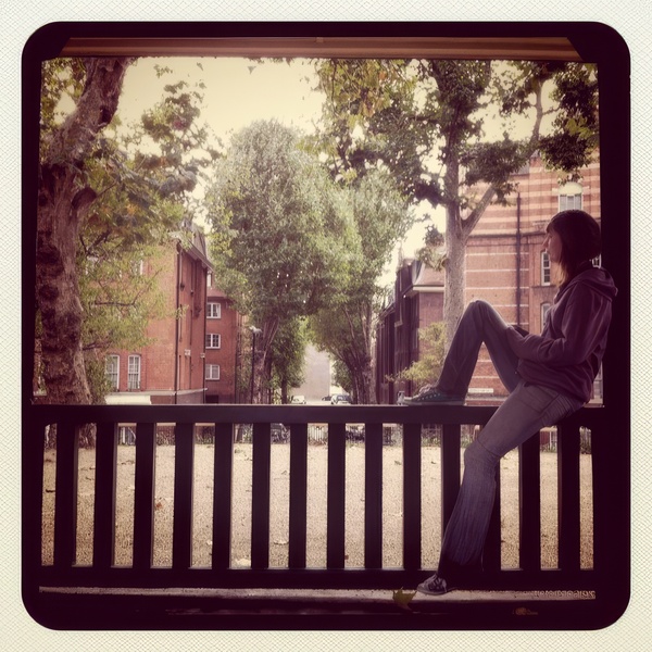 a woman sitting on a bench looking out a window