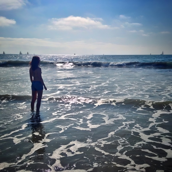 a woman standing in the ocean with a surfboard