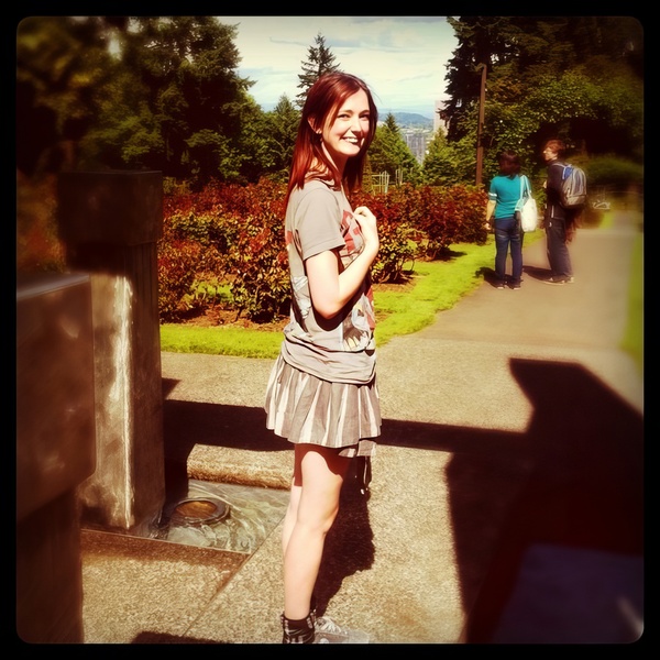 a woman standing in a park with a cellphone