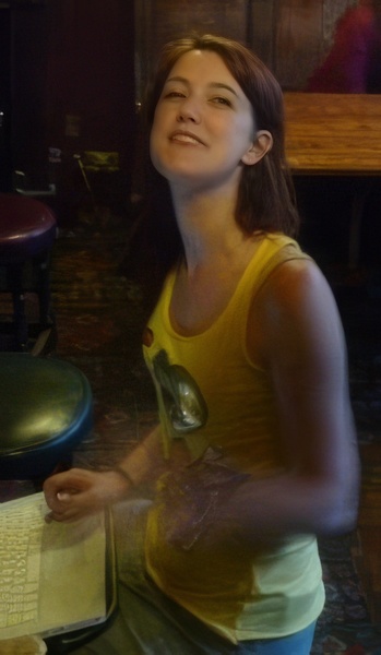 a woman sitting at a table with a pizza