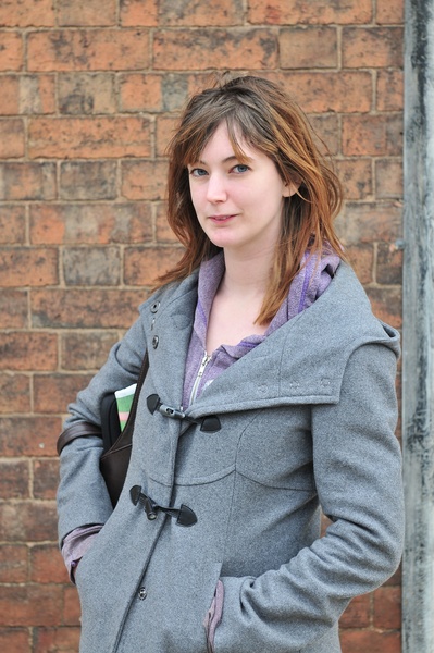 a woman standing in front of a brick wall