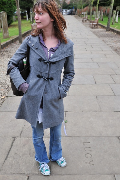 a young girl standing on a sidewalk with her hands in her pockets