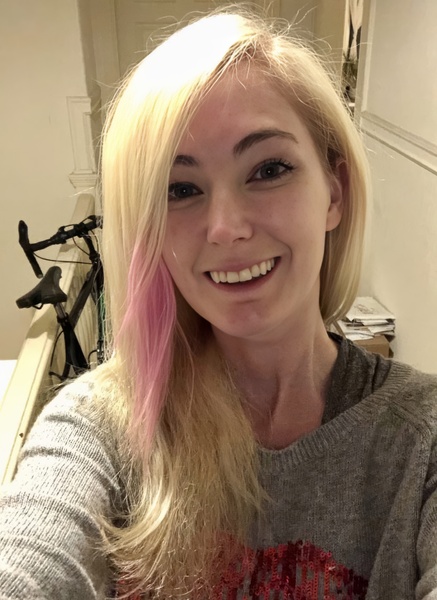 a woman with pink hair and a grey sweater