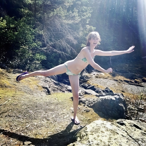 a woman in a bikini is standing on a rock