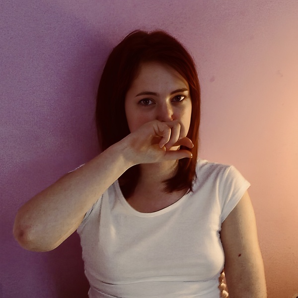 a woman sitting on a bed with her finger in her mouth