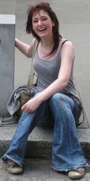 a woman sitting on a concrete bench with her hand in her mouth