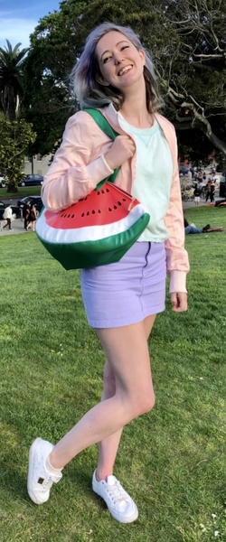 a woman in a pink shirt and purple skirt holding a watermelon