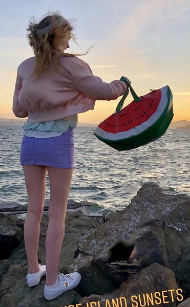 a woman standing on a rock with a watermelon