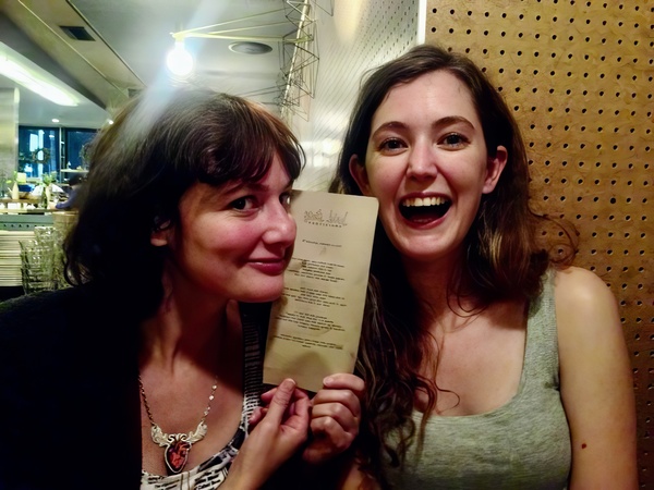 two women are smiling and holding a menu