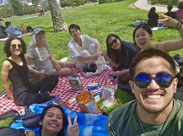 a group of people sitting on a blanket in the grass