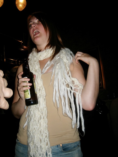 a woman holding a bottle of beer and a scarf