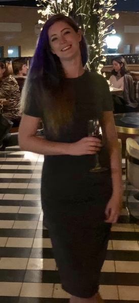 a woman standing in a restaurant holding a glass of wine