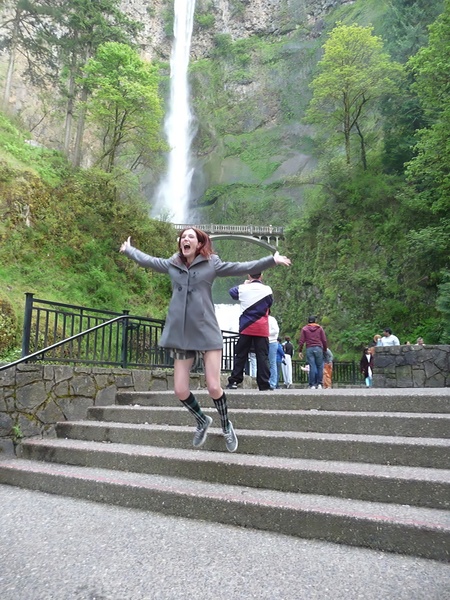 a woman is jumping up some stairs in front of a waterfall