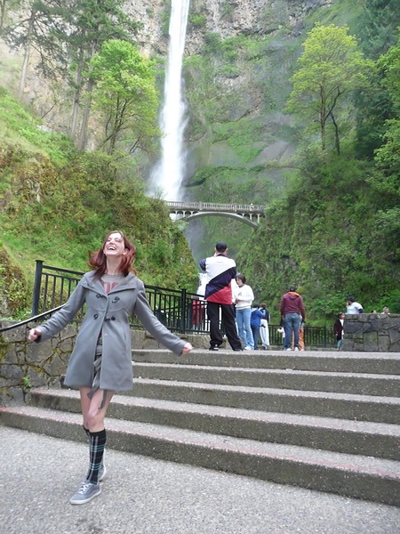 a woman in a gray coat is walking up some stairs Ly re ‘ by