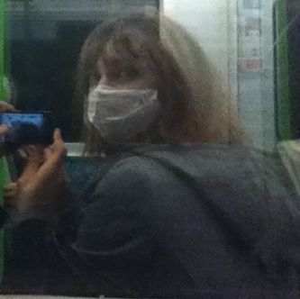 a woman wearing a face mask while riding a subway train