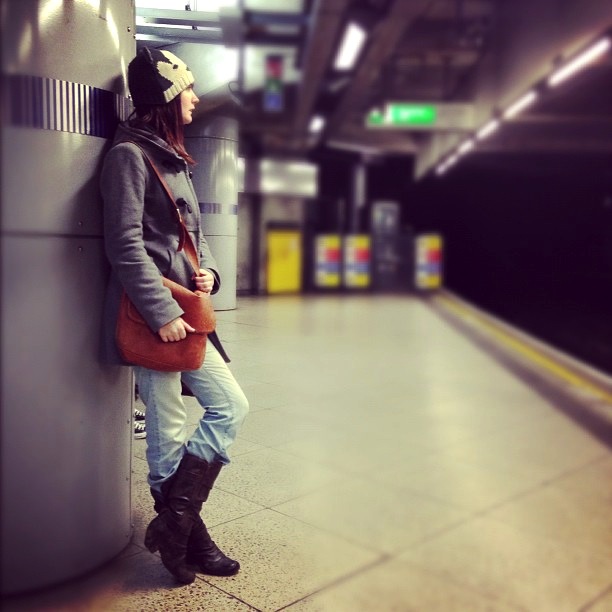 a woman is standing in a subway station