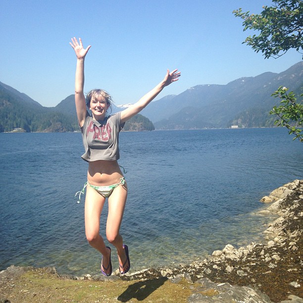 a woman jumping off a rock into the water