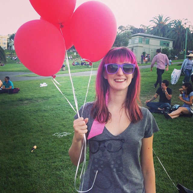 a woman holding two red balloons