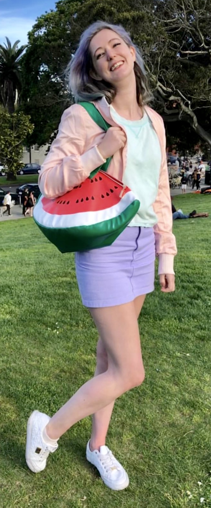 a woman in a watermelon outfit is walking across the grass