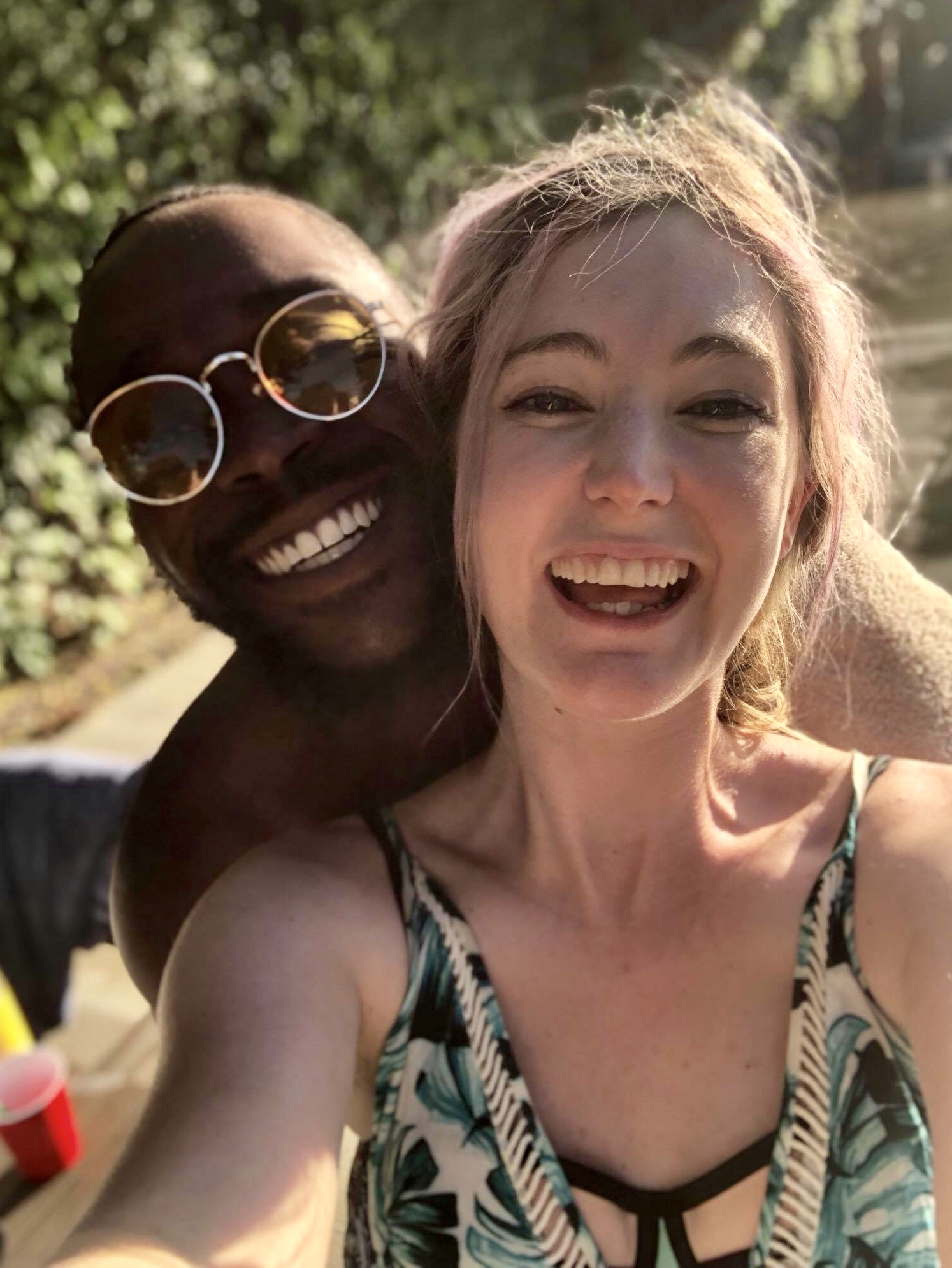 a woman in a bikini top and sunglasses smiles at the camera