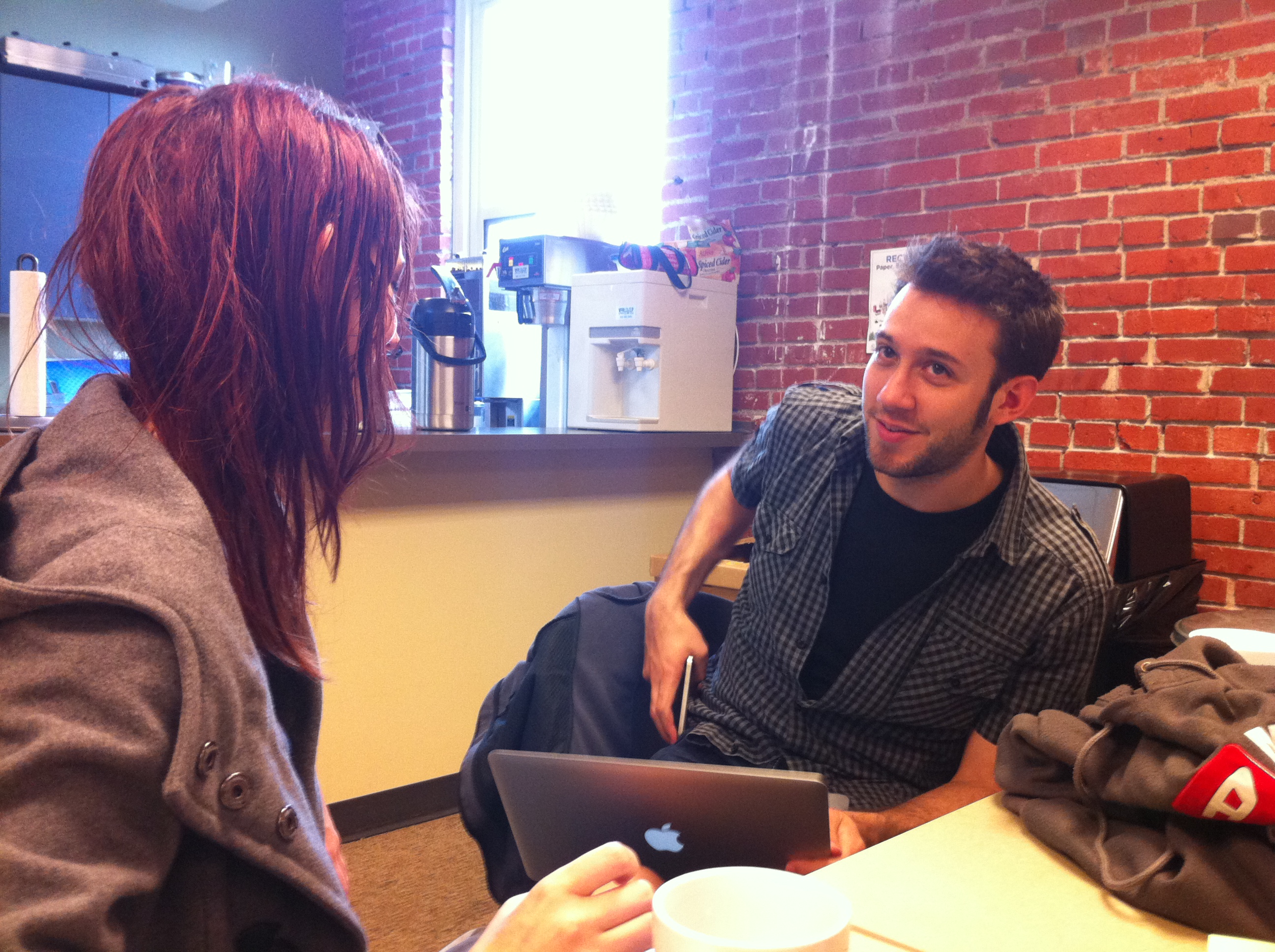 a man and woman sitting at a table with a laptop