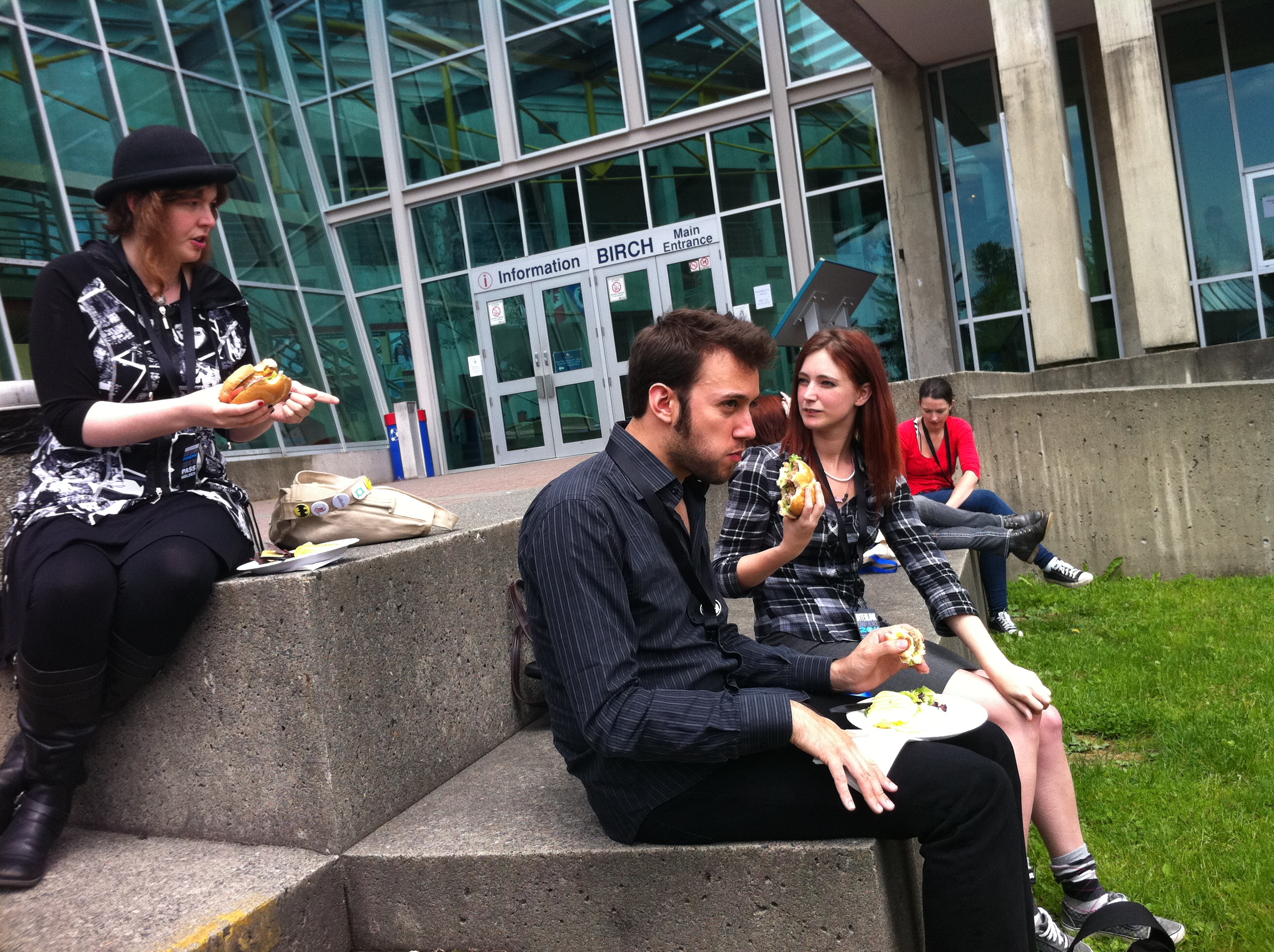 a man and woman sitting on a concrete bench eating food