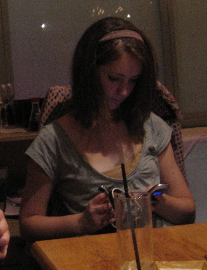 a woman sitting at a table with a cellphone