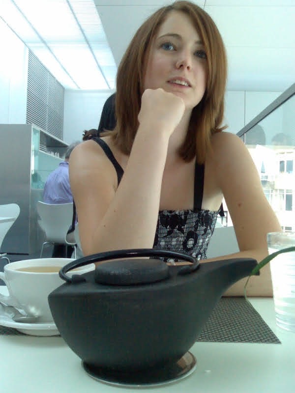 a woman sitting at a table with a pan of food