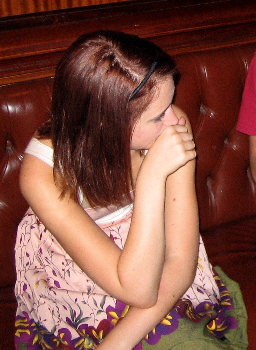 a girl sitting on a couch with her eyes closed