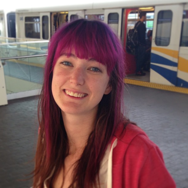 a woman with pink hair and a red sweater