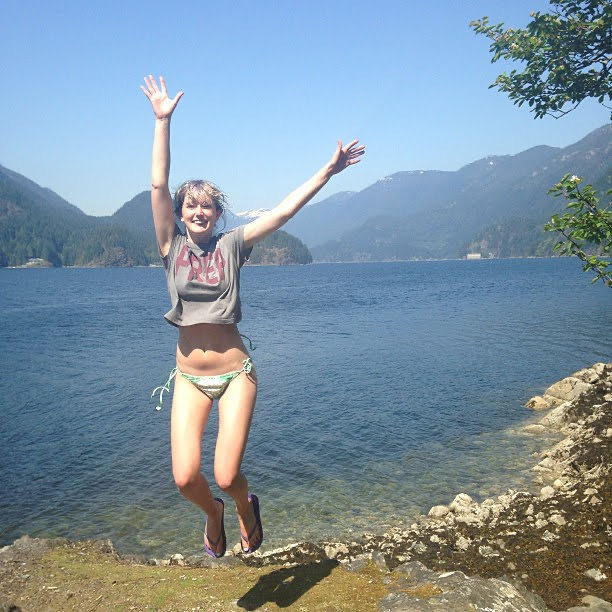 a woman jumping off a rock into a lake