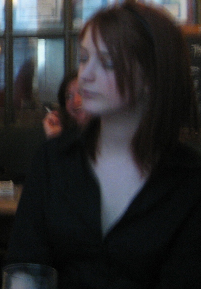 a woman sitting at a table with a drink