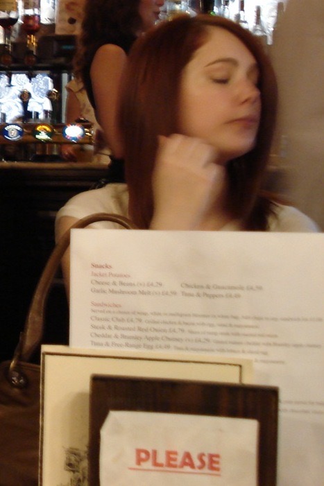 a woman holding a sign in front of a bar